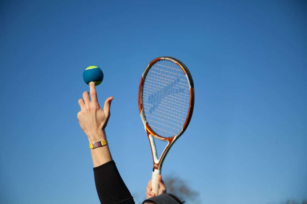 person holding red and white tennis racket